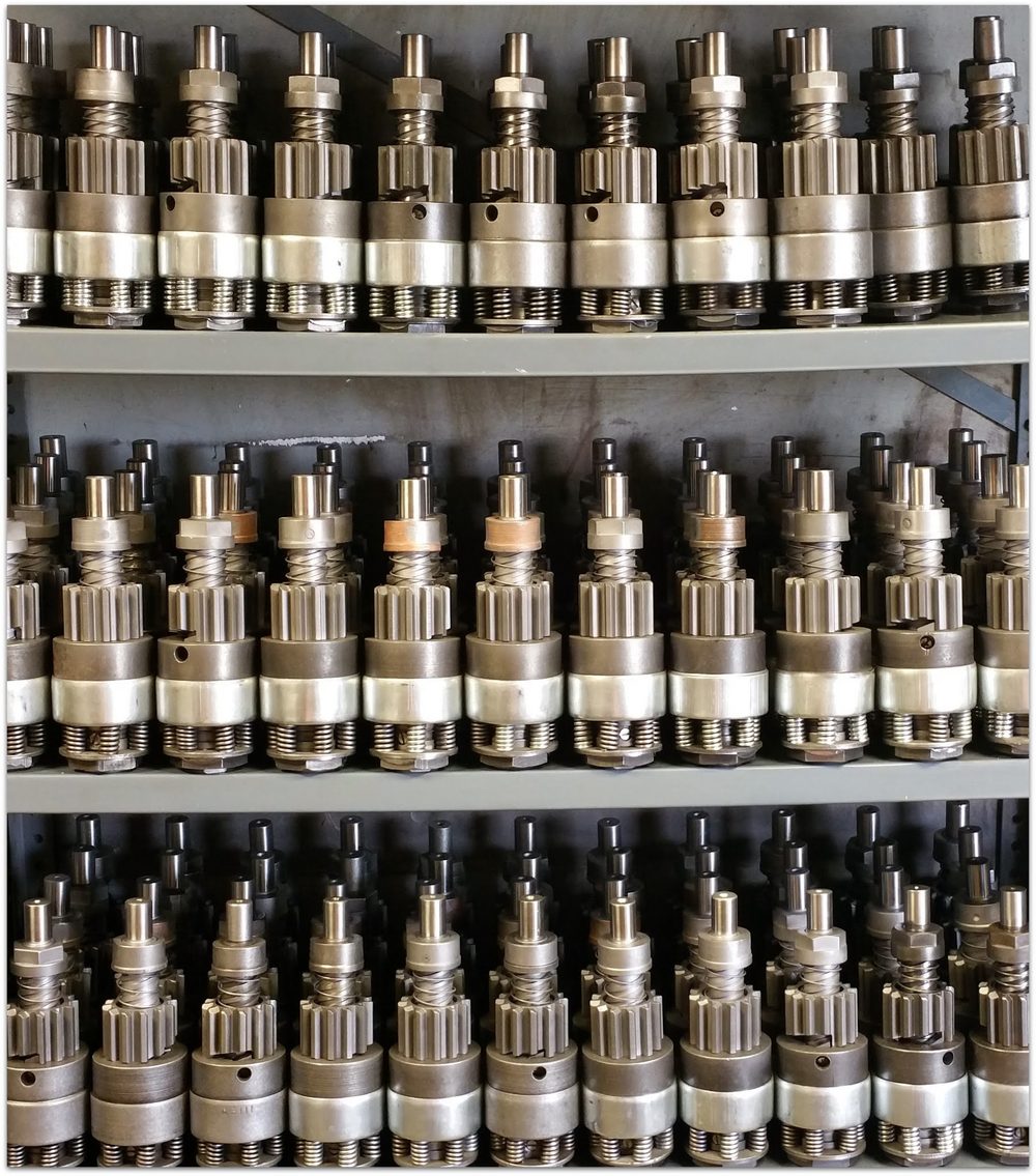 Rows of air starter pinion and drive assemblies stored on workshop shelving